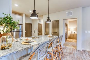 a kitchen with a long counter with chairs and a sink at The Beck at Hidden River, Tampa, FL
